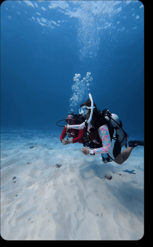 Two divers swimming together over clear sand during a Nusa Penida training dive