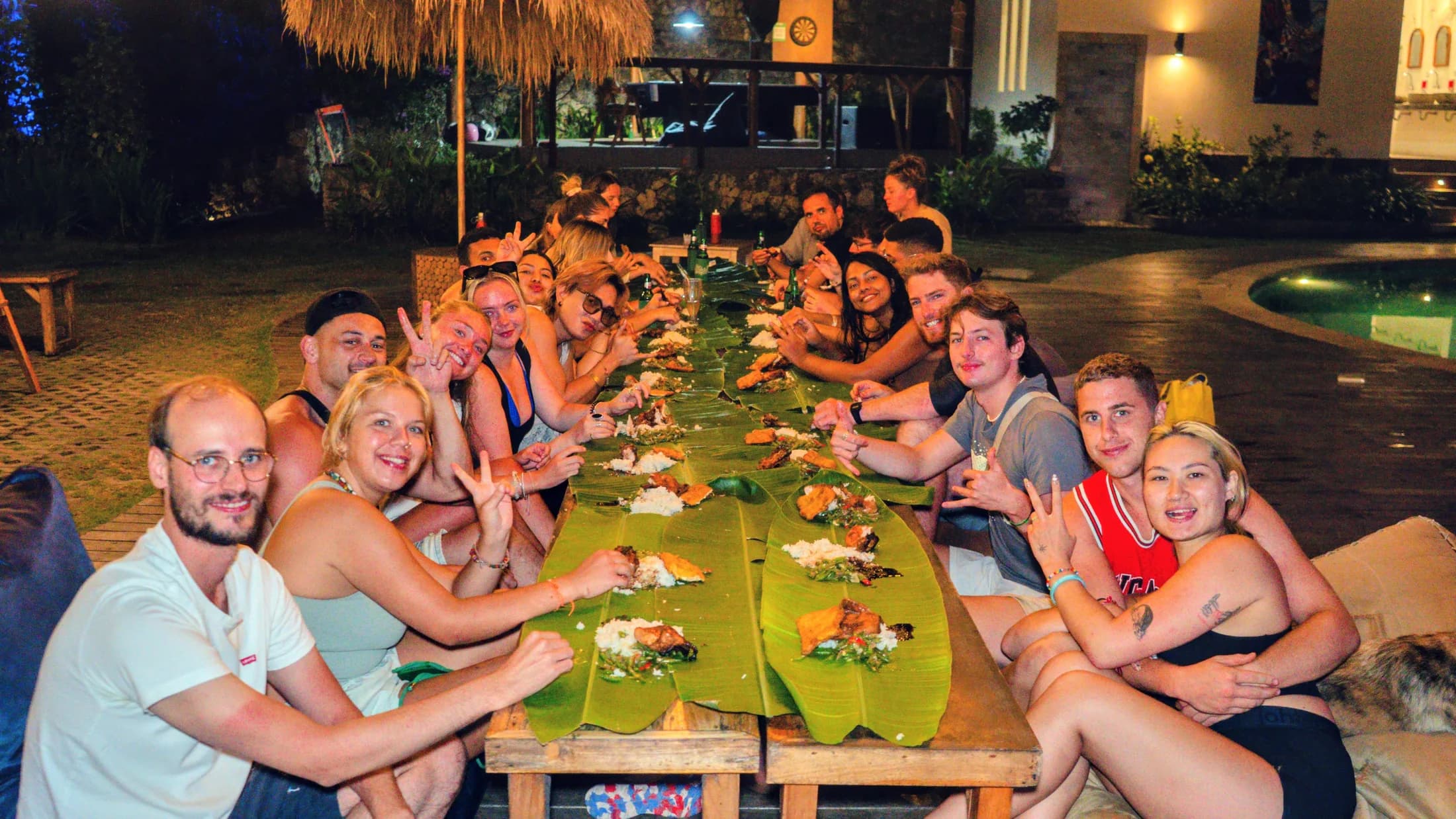 Guests sharing a communal dinner beside The Penida Project pool
