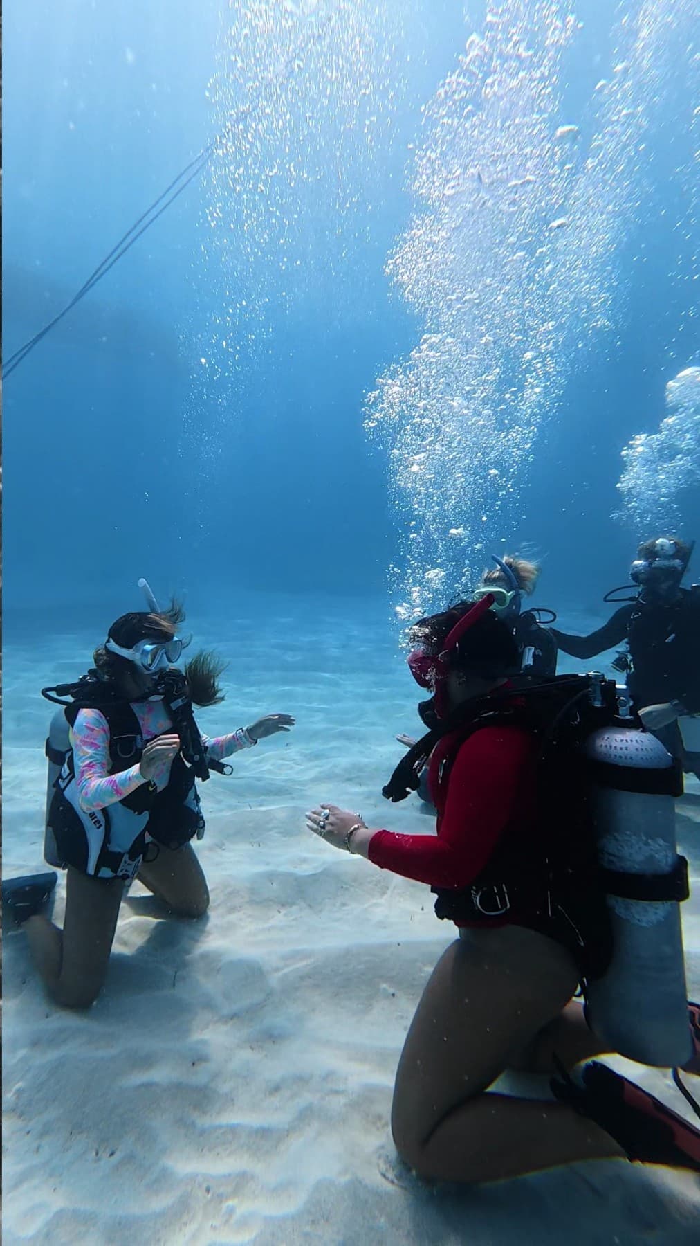 Dive instructor guiding students during an underwater lesson in clear water