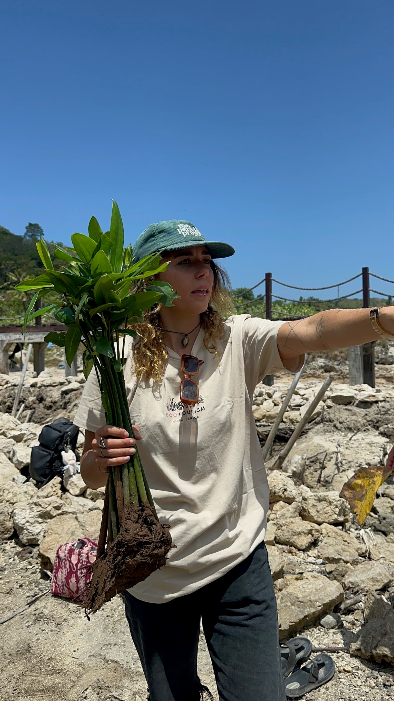 A guest holding mangrove seedlings on the shore