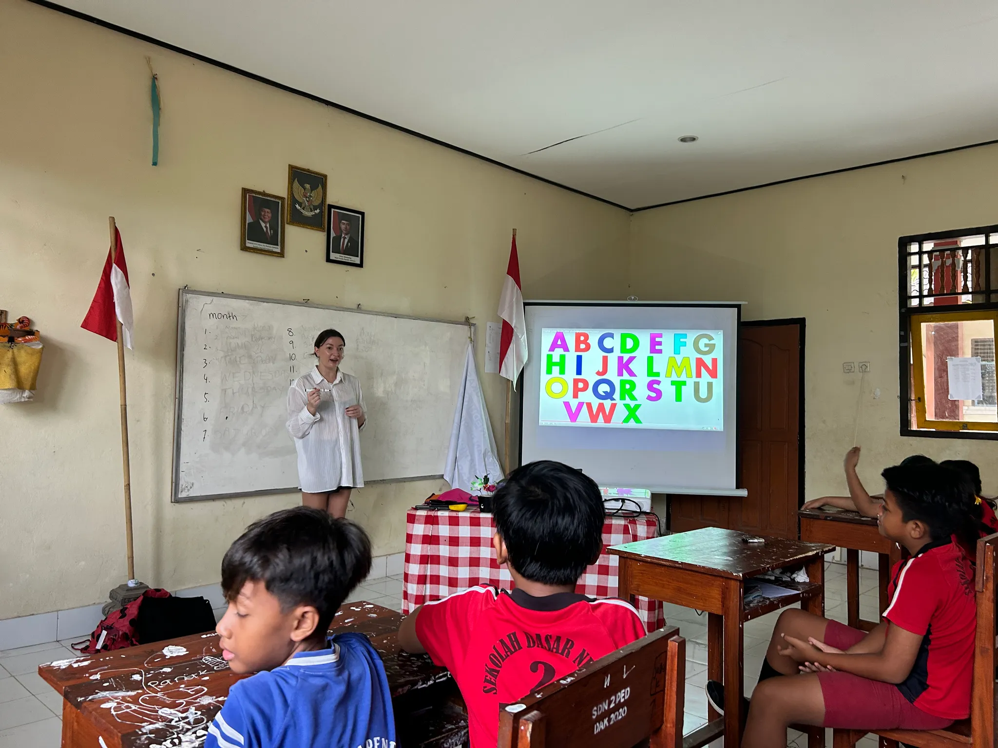 A guest helping with an alphabet activity in a classroom