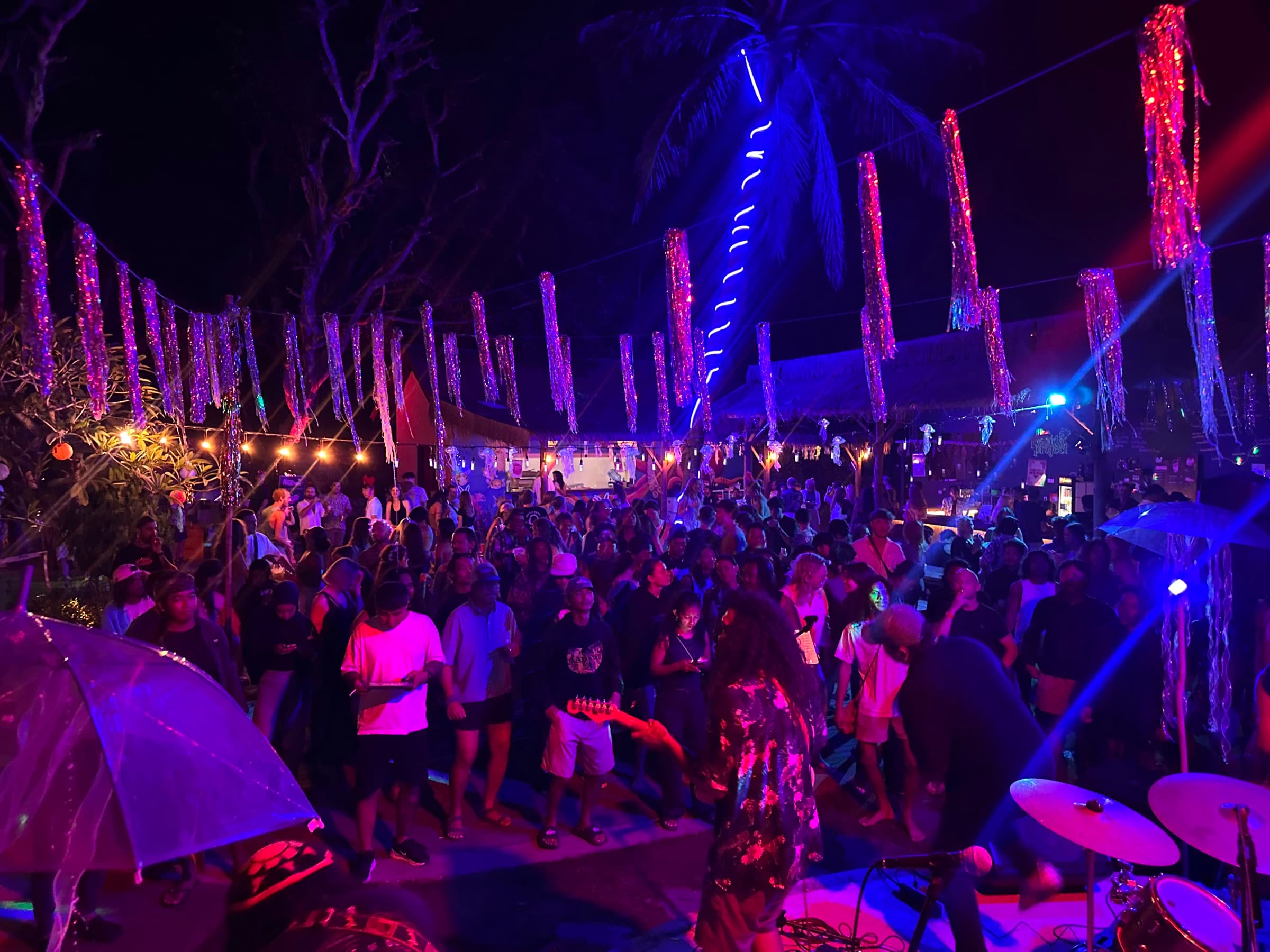 Crowd dancing beneath neon lights at The Penida Project Full Moon Party in Nusa Penida